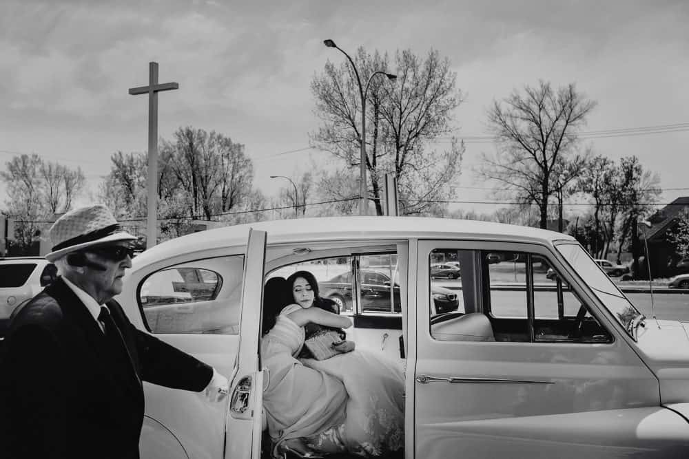 bride being hugged in vintage car before ceremony