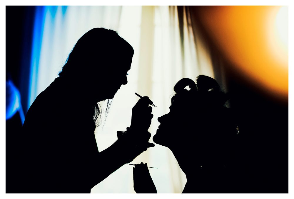 silhouette of a bride having false eyelashes applied