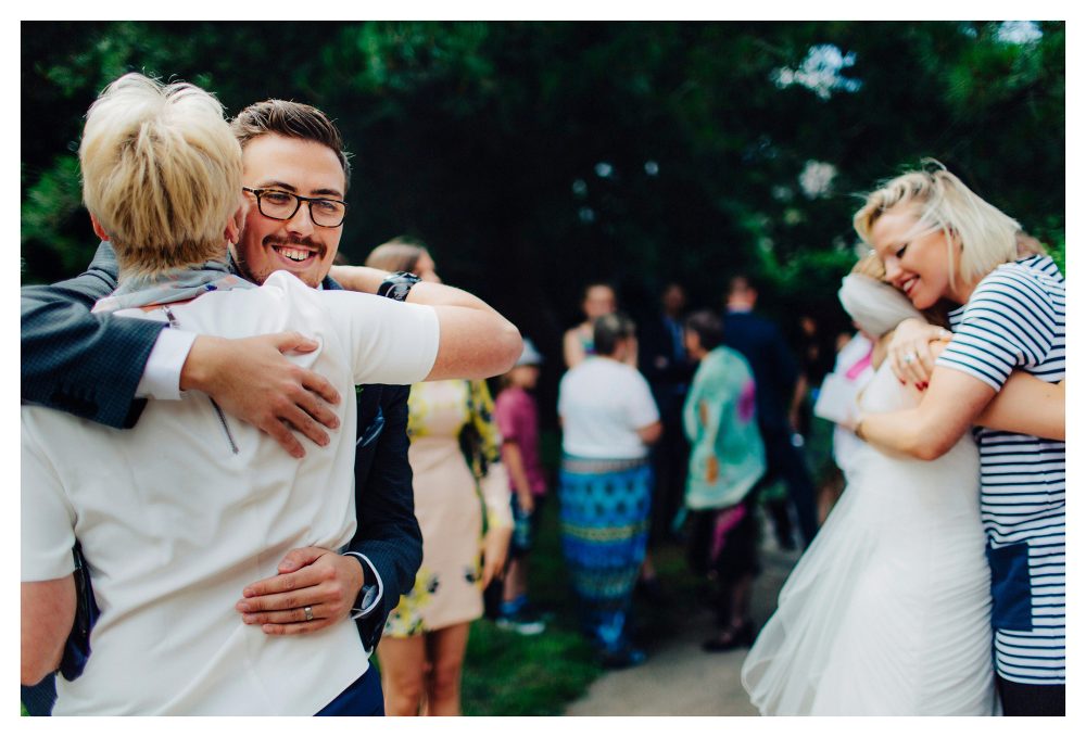 relaxed documentary wedding photography with guests hugging the couple