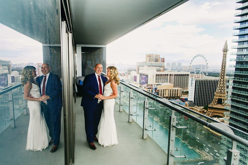 A bride and groom laughing on a balcony overlooking Las Vegas