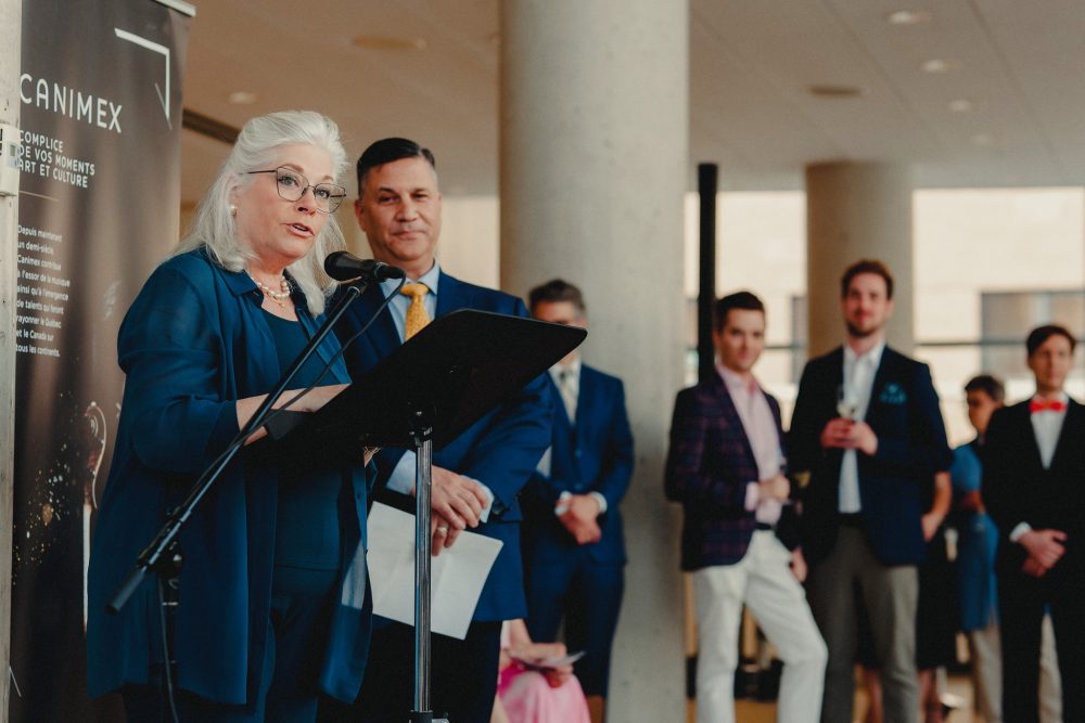 A woman speaking into a microphone at an event in Montreal.