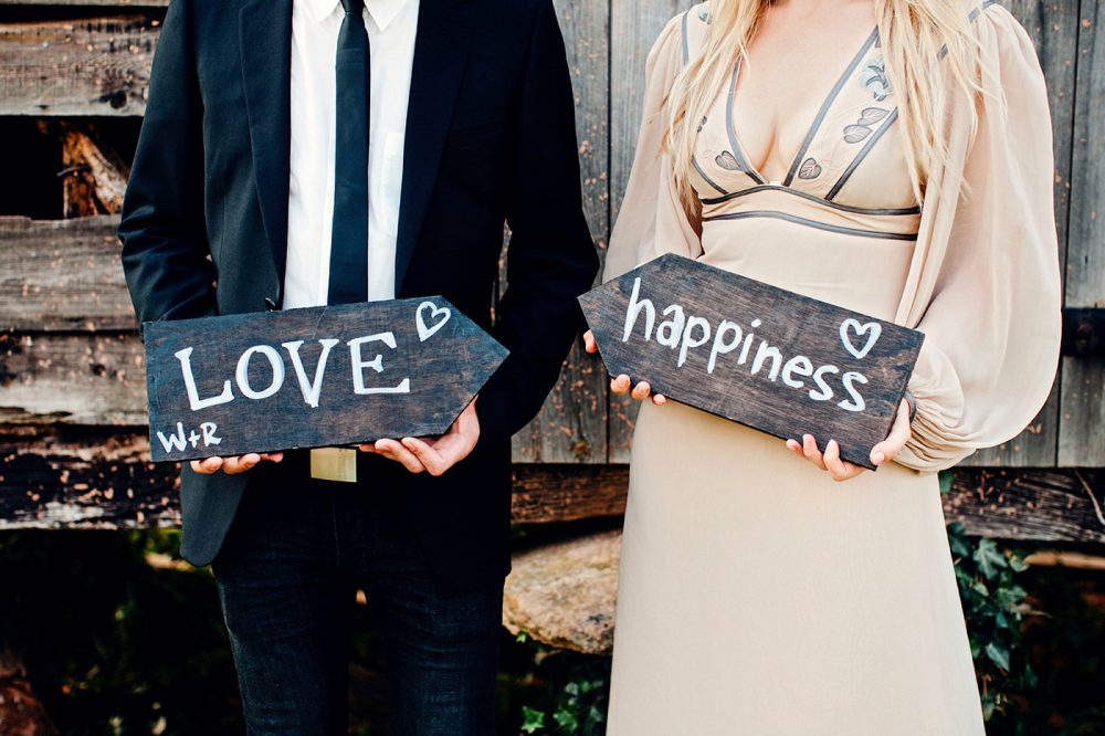 couple holding love and happiness signs in vintage wedding outfits