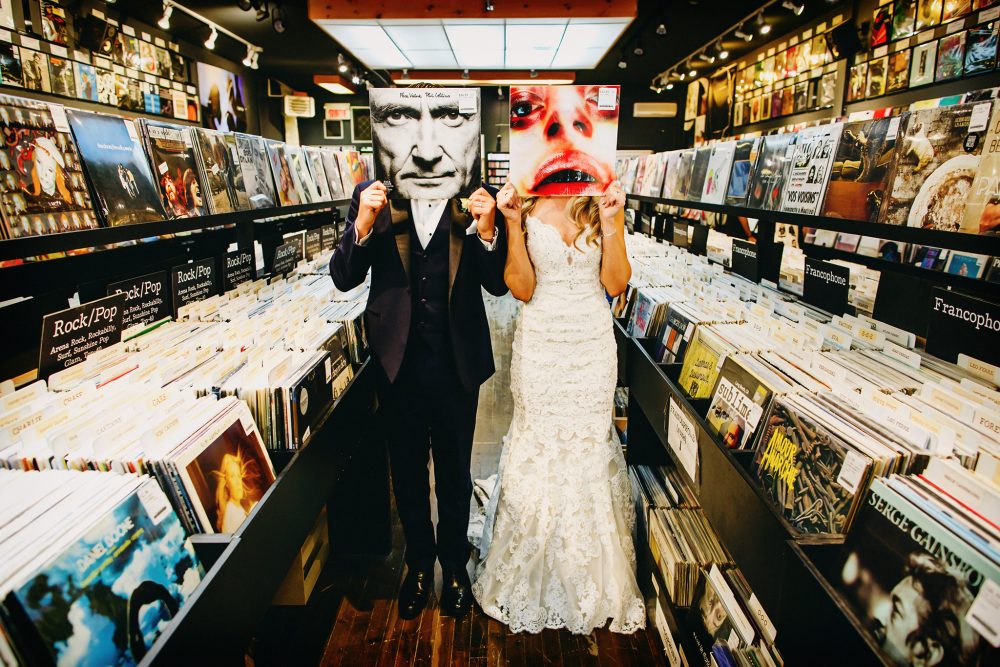 wedding couple hide behind record covers in a music store