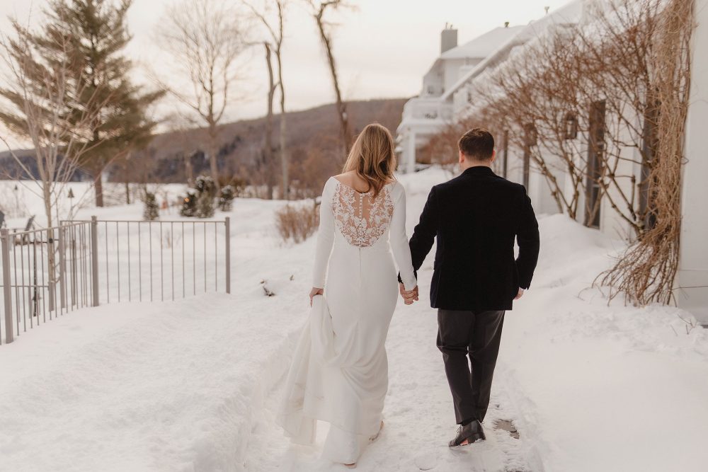 Bride and groom walk in the snowy grounds of Manoir Hovey
