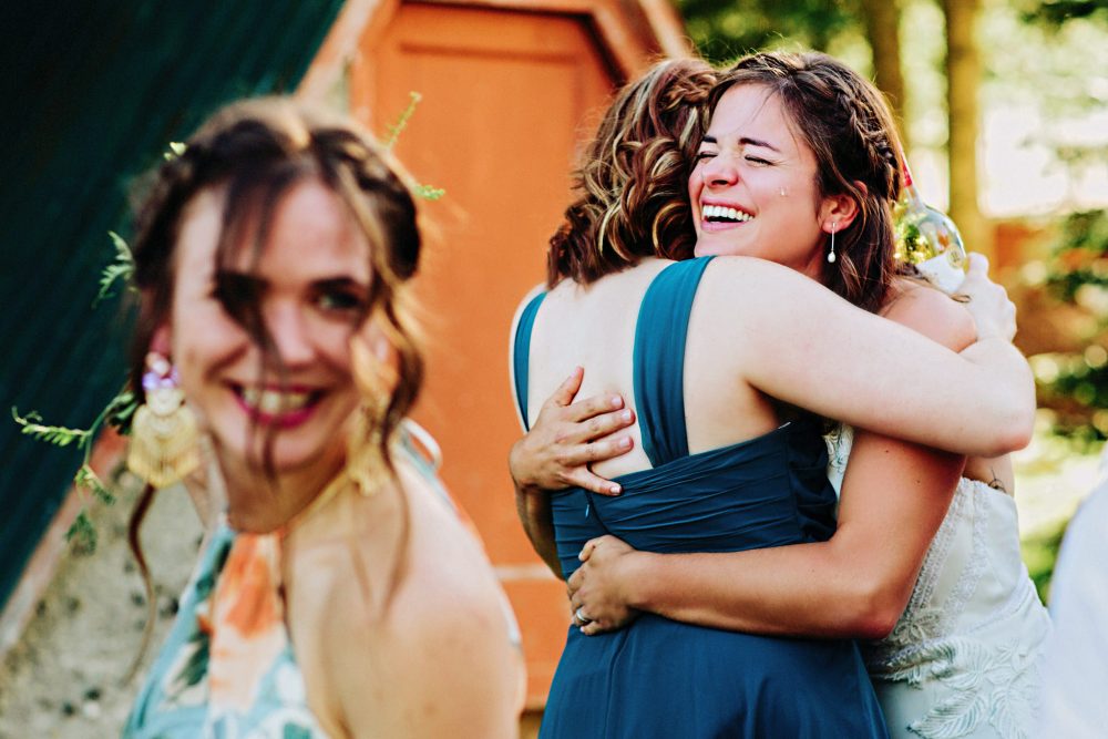 A bride hugs a guest as a tear rolls down her cheek